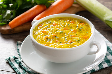 Chicken noodle soup in white bowl on wooden table	