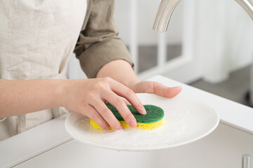 Woman housewife is doing the dishes at home kitchen.