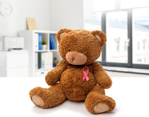 Wall Mural - medicine, healthcare and oncology concept - teddy bear toy with pink breast cancer awareness ribbon over medical office at hospital background