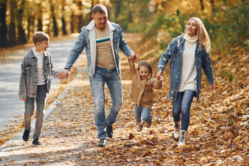 Wall Mural - Near the road. Happy family is in the park at autumn time together