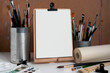 Art equipment. Tools and accessories for painting. A variety of brushes, paints, paper in a roll. Wooden easel with workspace accessories on a white table.  A blank canvas for presentation. Mockup.