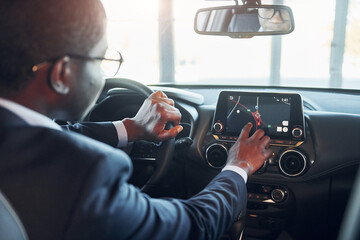 Vehicle interior. Young african american businessman in black suit is in the automobile