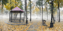 Fog In The Autumn Park. A Gazebo In The Fog Among Fallen Yellow Leaves And Bare Trees