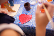 Children's Creativity, A Child Decorates A Wooden Decoration With Paints And A Brush. Figurine In The Shape Of A Heart.
