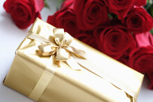 Big Golden Gift Box On The Background Of Red Roses