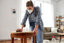 Furniture Renovation, Diy And Home Improvement Concept - Woman In Respirator Sanding Old Wooden Table With Sponge