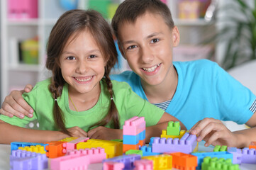 Wall Mural - Brother and sister playing with colorful plastic blocks together