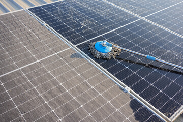 Wall Mural - Man using a mop and water to clean the solar panels that are dirty with dust and birds' droppings to improve the efficiency of solar energy storage.