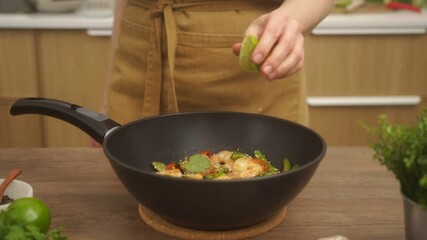 Wall Mural - Crop faceless woman adding lime juice to stir fried prawns