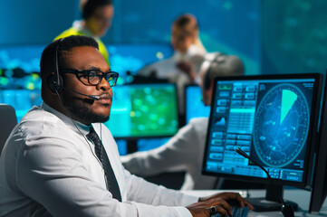 Wall Mural - Aircraft flight control officer monitors the approach of aircraft from control tower. Air services office is equipped with navigation systems, radars and computer stations. Aviation concept.