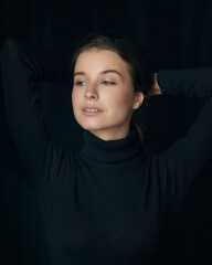 Brown haired lady model with expressive look in black sweater posing on black background in studio closeup