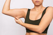 © Марина Демешко - Cropped shot of a young caucasian woman grabbing skin on her upper arm with excess fat isolated on a white background. Pinching the loose and saggy muscles. Overweight concept