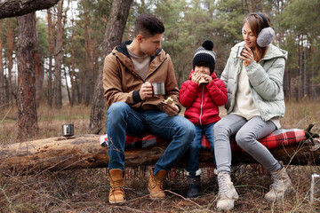 Wall Mural - Happy family with sandwiches and hot drinks in forest