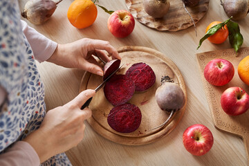 Wall Mural - Cutting beetroot, apples and oranges to prepare fresh fruit and vegetable juice