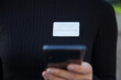 © jandruk - Close up of a young businesswoman with an ID card on her chest and holding a cell phone outdoors