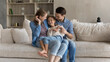 © fizkes - Loving caring happy young couple parents tickling adorable little preteen kid daughter, having fun sitting on cozy couch together in modern living room, enjoying carefree playtime weekend activity.