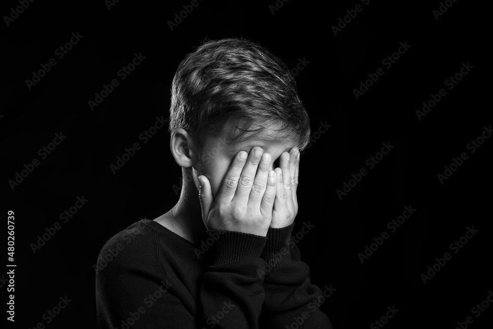 Crying little boy on black background