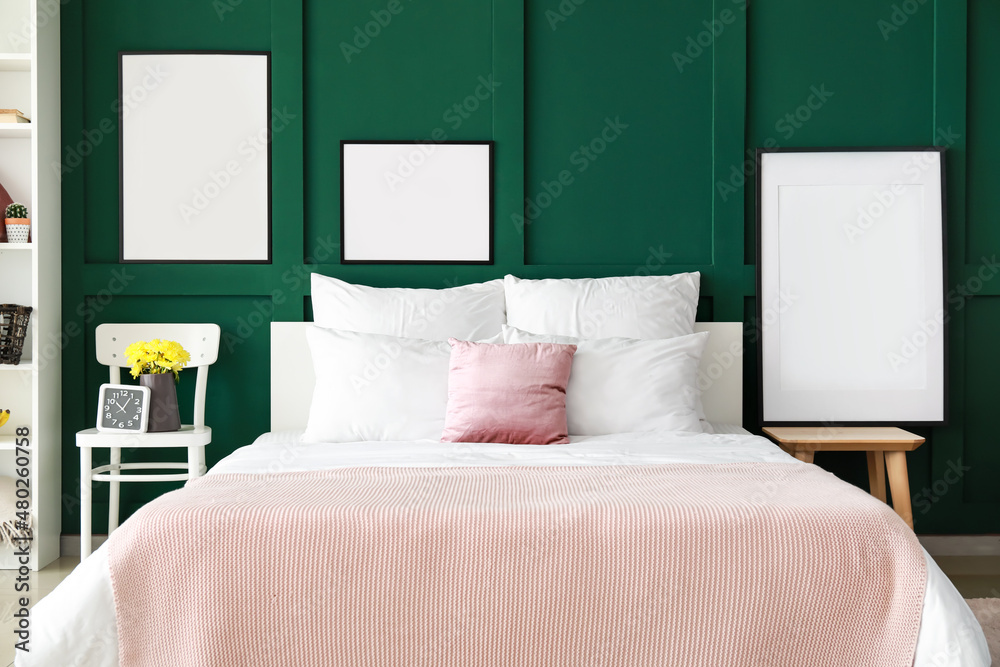 Stylish bedroom with comfy bed and blank posters