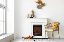 Interior Of Light Room With Modern Fireplace, Armchair And Pumpkins