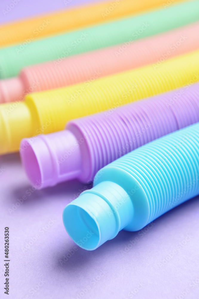 Different colorful Pop Tubes on purple background, closeup