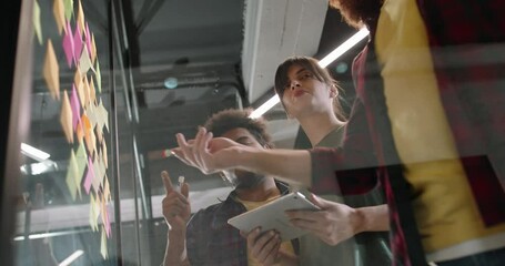team of young developers brainstorming, looking for creative ideas and writing them on sticky notes.