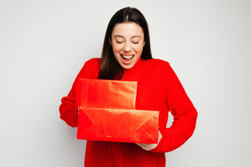 Wall Mural - Young woman with black hair holding red gift boxes against the white background. Concept of the Valentine's Day celebration