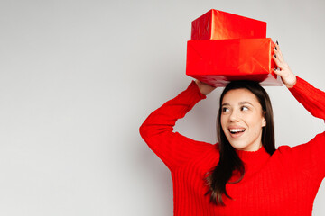 Wall Mural - A girl is standing at the white background with red present boxes on her head. The girl looks cheerful and happy. Concept of the Valentine's Day