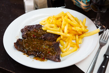 Wall Mural - Roasted beef steak with side dish of crispy fries and Argentinian chimichurri sauce