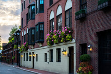 Row Of Red Brick Wall Apartment Buildings With Flowers At Window And Lanterns