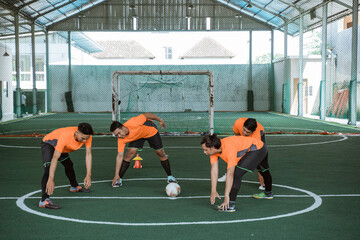 Wall Mural - four futsal players stretching their legs in the middle court