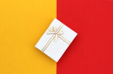 The Gift Box Stands At The Same Time On The Border Of Two Colors, Yellow And Red.
