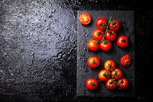 Fresh Tomatoes On A Branch On A Stone Board. On A Black Background. High Quality Photo