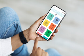 Poster - Smart home control concept. Black woman using mobile phone cropped
