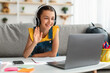 © Prostock-studio - Girl in headphones using laptop, waving to webcam