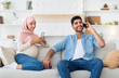 © Prostock-studio - Pregnancy and technology concept. Young muslim husband and his pregnant wife resting with smartphones at home