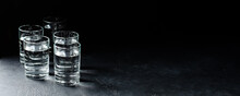 Glasses Of Vodka Are In A Row On Dark Background. Selective Focus. Copy Space