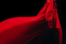 Cropped Female Figure Dressed In A Creative Long Red Fancy Outfit, Costume Pants And Jacket Walking On Black Background. Fashion Week Details