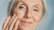 Close-up Portrait of Beautiful Senior Woman Gently Applying Under Eye Face Cream. Elderly Lady Makes Her Skin Soft, Smooth, Wrinkle Free with Natural anti-aging Cosmetics. Product for Beauty Skincare