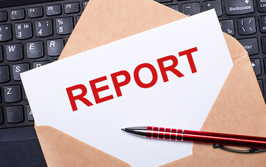 Fototapete - White card with the text REPORT in a craft envelope on a work desk with a modern laptop keyboard and burgundy pen. Flat layout of the workplace.