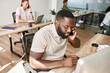 © Svitlana - Black man talking on smartphone while working