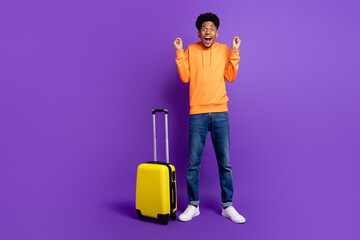 Wall Mural - Full body photo of cheerful young happy afro american man winner luggage wear jeans hoodie isolated on purple color background