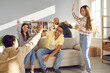 © Studio Romantic - Give me five. Two cheerful multiracial men give high five to each other while having fun at home with friends. Group of excited millennial friends sitting in living room and having fun together.