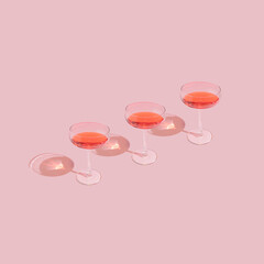 Three elegant wine glasses on pastel pink background. Trendy and minimal romantic Valentine's day aesthetic.