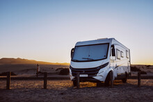 Big Motorhome Camper Parked Off Road With Desert And Blue Sky In Background. Travel Lifestyle Camping Car And Freedom. Van Against Sunlight Parked Off Road. Concept Of Wanderlust Vanlife Travelers