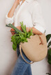 © Dina - person in white shirt and jeans holding eco jute reusable bag with bunch of green basil and lettuce. Grocery shopping for vegetables - healthy lifestyle
