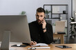 © New Africa - Man talking on phone while working at table in office