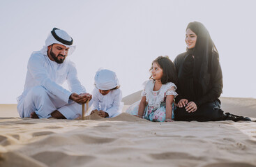 Wall Mural - Happy family spending a wonderful day in the desert making a picnic. People from the emirates with traditional clothes making a safari in Dubai