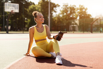 Sporty black woman in yellow sportswear holding shaker