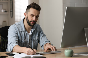 Man working with computer at table in home office