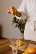 © Dina - woman making lemon water in the kitchen at home - healthy eating and lifestyle